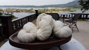 Yarn balls of sustainable, natural cotton with the Mekong River in the background. The image is taken at Tohsang Sustainable Cotton Village in Thailand for Rare & Fair. 
